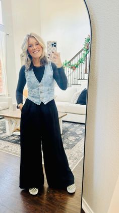 a woman standing in front of a mirror taking a selfie with her cell phone