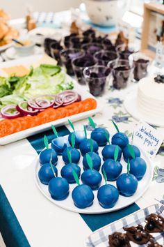 blueberries are arranged on a white plate with green onions and lettuce in the background