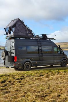 the van is parked on the side of the road by the water with its roof up