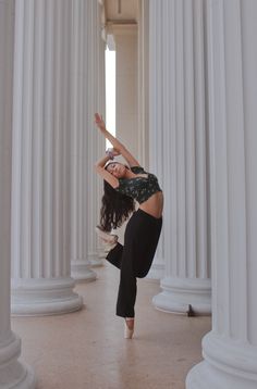 a woman is doing a handstand in front of some white pillars and columns