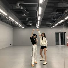 two people standing in an empty room with one holding up the other's hand