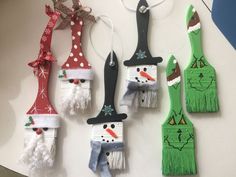 christmas decorations made out of toilet paper hanging from hooks on a wall with snowmen and santa hats