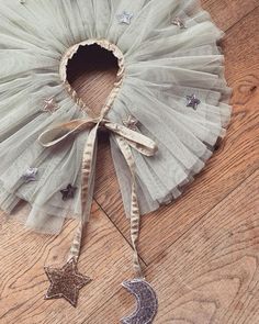 a white tutu with stars and a crescent hanging from it's side on a wooden floor