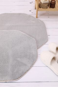 two gray rugs sitting on top of a white floor next to a wooden bench