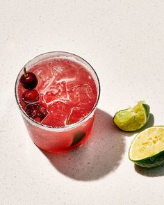 a drink with cherries and limes next to it