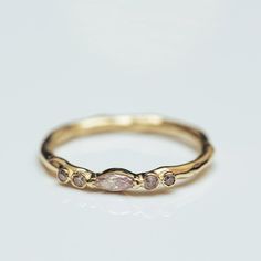 a gold ring with three stones on the side and one stone in the middle, sitting on top of a white surface