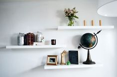 two white shelves with books, pictures and a globe on one shelf in front of the other