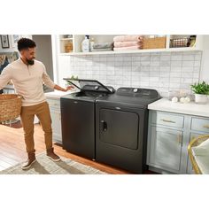 a man standing next to a washer and dryer in a kitchen