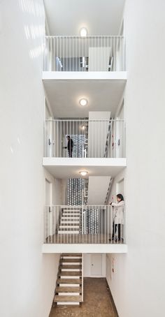 an apartment building with stairs leading up to the second floor and two people standing at the top