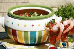 a bowl of soup with shrimp and garnishes in it on a table