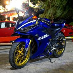 a blue and yellow motorcycle parked next to a red car