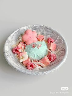 a bowl filled with heart shaped marshmallows and raspberries on top