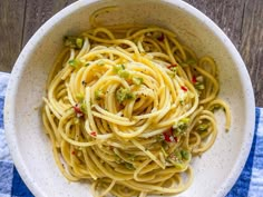 a white bowl filled with pasta and broccoli on top of a blue towel