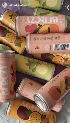 several cans of juice sitting on top of a bed next to each other in a pile