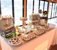 a table topped with lots of desserts next to a large glass window filled with windows