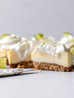 a piece of cheesecake with whipped cream and limes on the side next to a fork