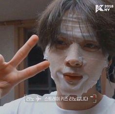 a young man with white face paint making the peace sign for his hand in front of him