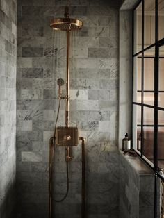 a shower head in the corner of a bathroom with marble tiles on the walls and floor