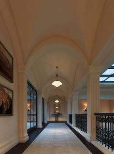 an empty hallway with railings and paintings on the walls