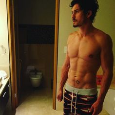 a shirtless man standing in front of a bathroom mirror with his hands on his hips