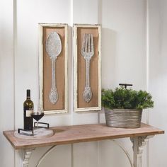 two silver utensils are hanging on the wall next to a potted plant