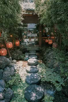 an outdoor garden with rocks and lanterns in the background, surrounded by greenery on either side