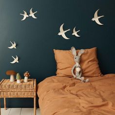 a bed room with a neatly made bed and birds on the wall next to it