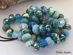 a bunch of glass beads sitting on top of a white table next to a piece of driftwood