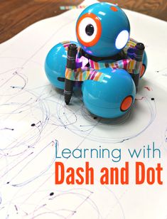 a blue toy car sitting on top of a white paper with the words learning with dash and dot