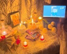 a table topped with candles and pictures next to a laptop computer on top of a table