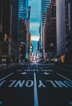 an empty city street at night with tall buildings