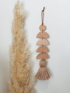 a wooden ornament hanging on a wall next to a dried plant with long tassels