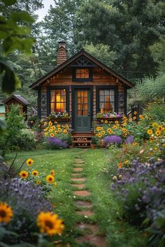 a small wooden cabin surrounded by lots of flowers and greenery in the front yard