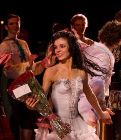 a woman in a white dress is holding flowers