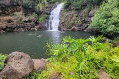 there is a small waterfall in the middle of this lake with people swimming under it