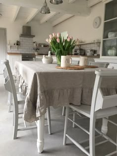 a table with some flowers on it in a room that has white walls and floors