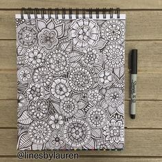 an adult coloring book with black and white doodles on it next to a pen