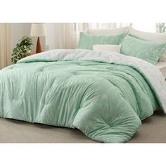 the comforter is green and has white trims on it, along with pillows