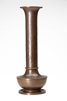 a tall metal vase sitting on top of a table