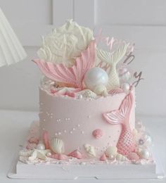 a pink and white cake decorated with seashells