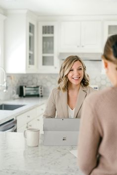 a woman sitting at a kitchen counter talking to another woman