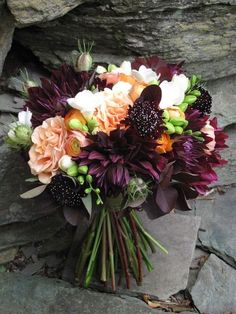 a bouquet of flowers sitting on top of a rock