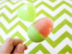 a hand holding a green and pink candy lollipop