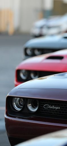 a row of red and black muscle cars parked next to each other in a parking lot