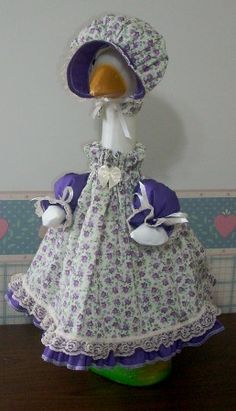 the doll is wearing a purple dress and hat