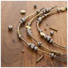 a necklace with gold and silver beads on a wooden table next to other jewelry pieces