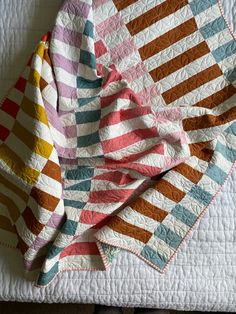 a multicolored quilt on top of a bed