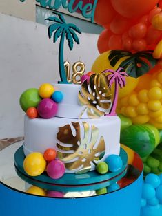 a three tiered cake decorated with palm trees and colorful candies is on display