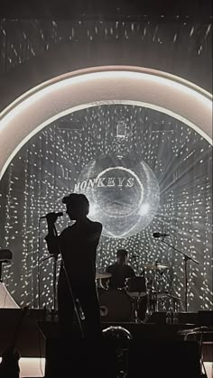 a man standing on top of a stage next to a microphone in front of a large screen