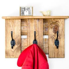 a coat rack with two coats hanging on it and a red umbrella in the foreground